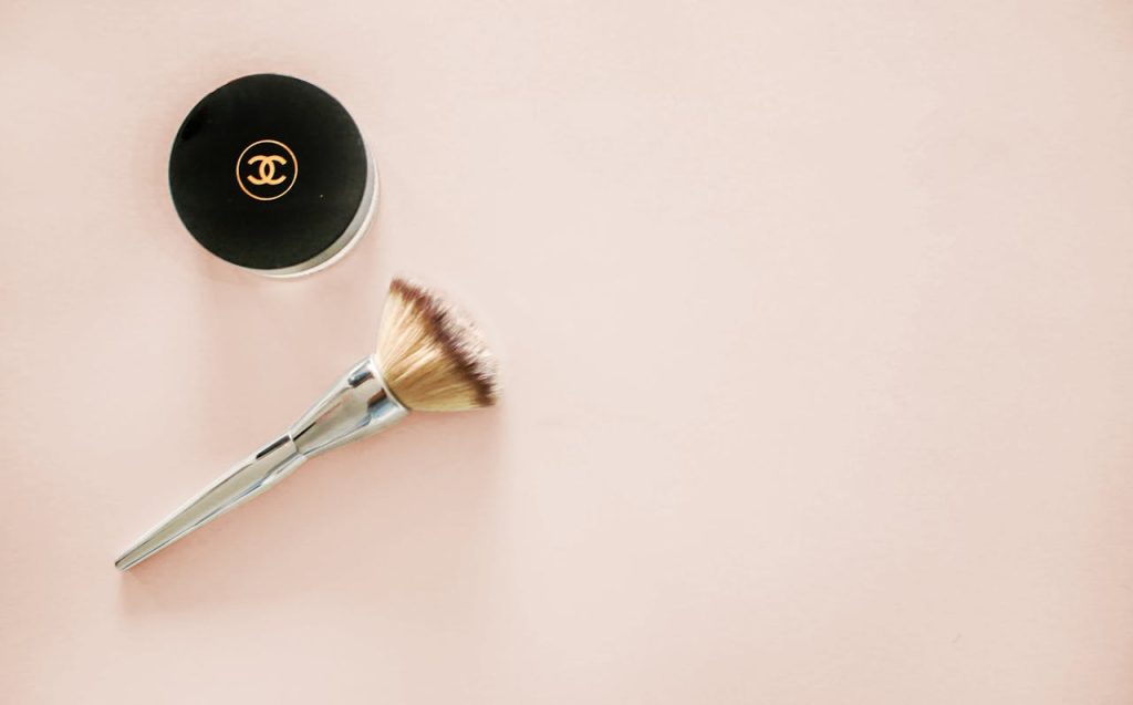 The Art of Drawing Readers In: Your attractive post title goes here Sophisticated flatlay of a makeup brush and branded cosmetic jar on a pastel background.